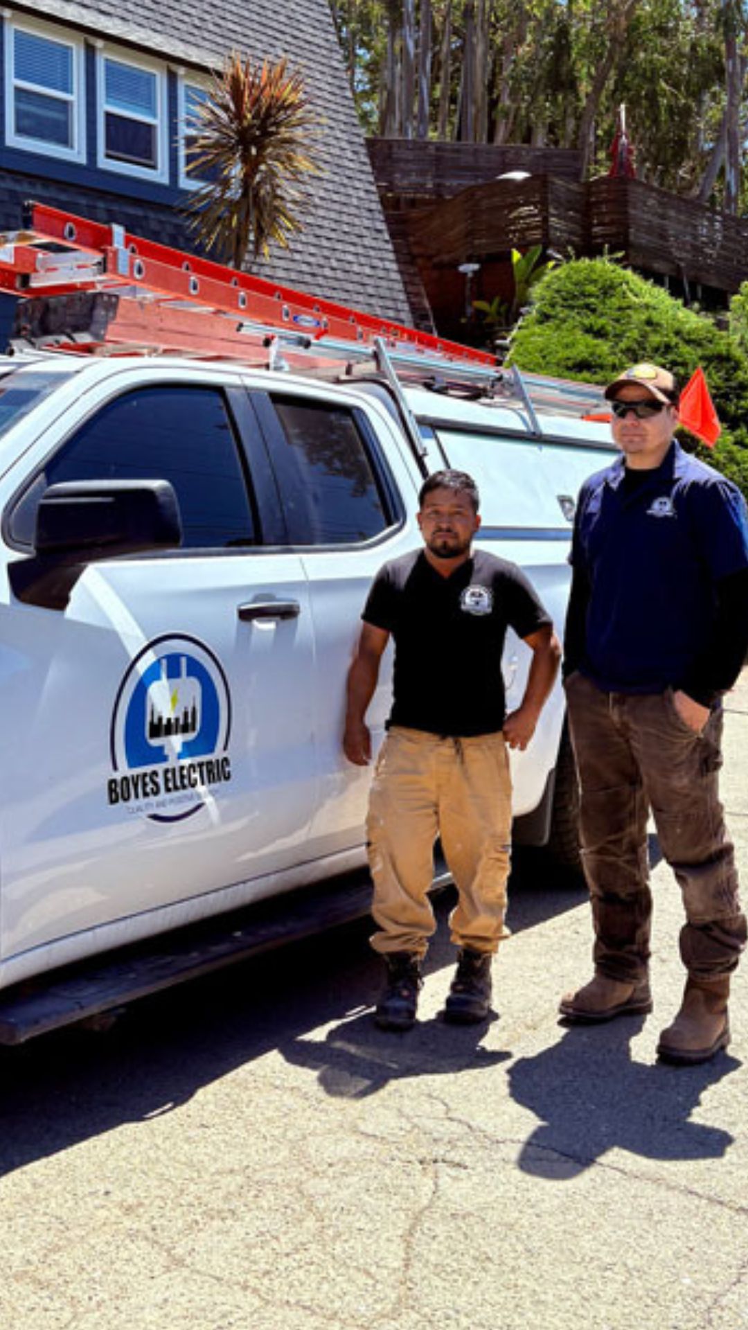 Boyes Electric electricians standing beside their work truck outside residential service call